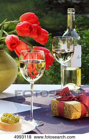White wine, gift and bunch of tulips on garden table View Large Photo Image Stock Photo - White wine, gift and bunch of tulips on garden table . Fotosearch