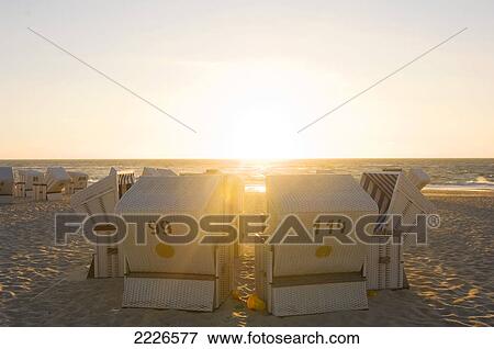 Stock Photo - Wicker chairs arranged on beach at dusk . Fotosearch