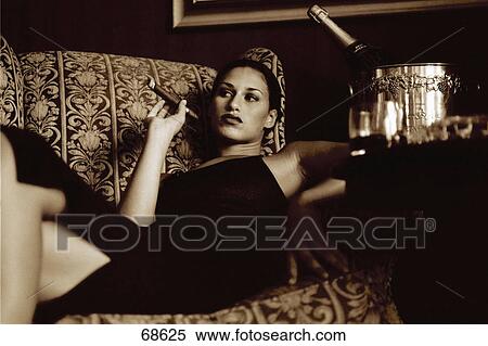 Stock Photography - Woman on couch smoking a cigar . Fotosearch