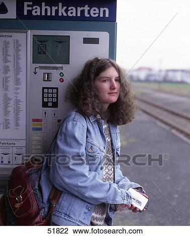 Stock Image - Young woman leaning against station ticket machine at railway platform, Germany . Fotosearch