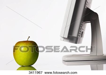An apple beside computer monitor in the workplace View Large Photo Image Stock Photo - An apple beside computer monitor in the workplace . Fotosearch
