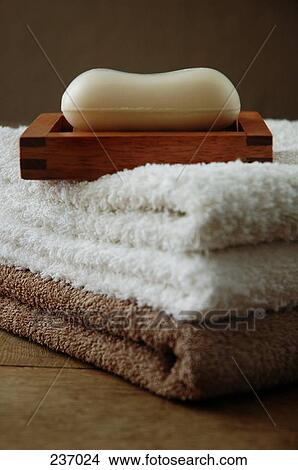 Picture - Bar of soap in soap dish on stack of folded towels . Fotosearch