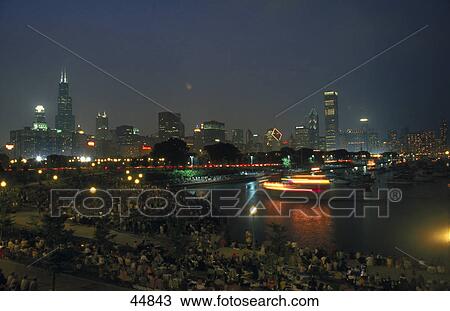Stock Image - Boat passing under bridge with city skyline at night, Grant Park, Chicago, Illinois, USA . Fotosearch