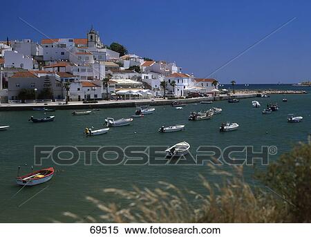 Stock Photography - Boats in sea with a town in the background, Ferragudo, Algarve, Portugal . Fotosearch