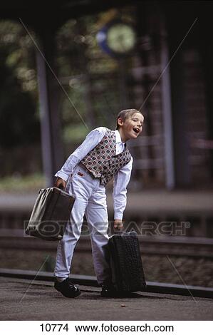 Picture - Boy with suitcases waiting at platform . Fotosearch