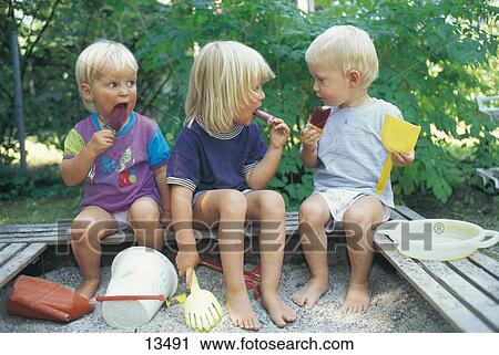 Boys and a girl sitting in a sandpit and eating ice cream View Large Photo Image Stock Image - Boys and a girl sitting in a sandpit and eating ice cream . Fotosearch