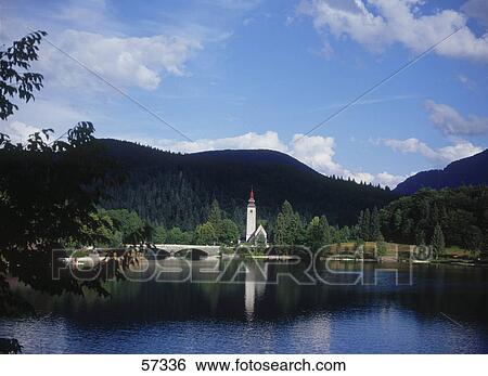 Stock Photograph - Bridge across a river leading to a church, Bohinj Lake, Triglav National Park, Slovenia . Fotosearch