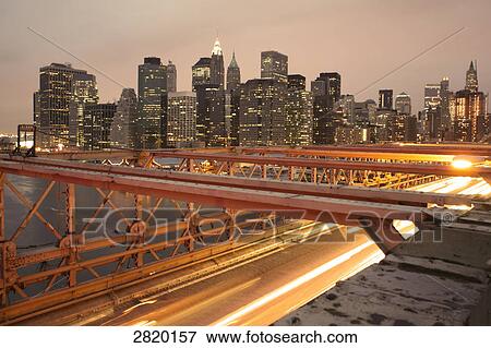 Stock Photo - Bridge and skyscrapers lit up at dusk, Brooklyn Bridge, Manhattan, New York City, New York State, USA . Fotosearch