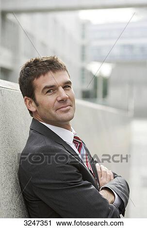 Businessman leaning against wall, waist up View Large Photo Image Stock Image - Businessman leaning against wall, waist up . Fotosearch