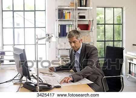 Stock Photo - Businessman reading a newspaper at his desk . Fotosearch