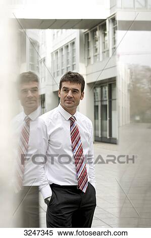 Businessman standing between reflective columns, three quarter length  View Large Photo Image Stock Photography - Businessman standing between reflective columns, three quarter length . Fotosearch