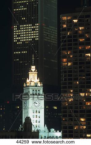 Stock Photo - Clock tower in city lit up at night, Wrigley Tower, Aon Building, Chicago, Illinois, USA . Fotosearch