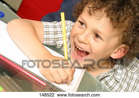 Stock Image - Close-up of boy drawing on paper and laughing . Fotosearch