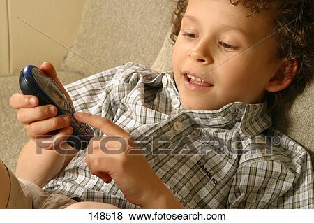 Stock Photo - Close-up of boy using mobile phone on couch . Fotosearch