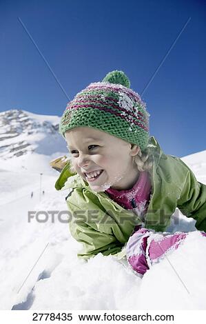 Stock Photography - Close-up of girl lying on snow and smiling . Fotosearch