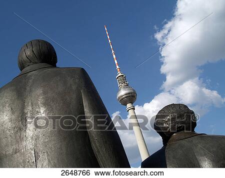 Stock Photograph - Close-up of Marx-Engels monument with tv tower in background, Alexanderplatz, Berlin, Germany . Fotosearch