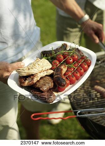 Close-up of person's hand holding sausages and cherry tomatoes on plate View Large Photo Image Stock Photo - Close-up of person's hand holding sausages and cherry tomatoes on plate . Fotosearch
