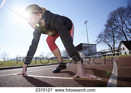 Stock Photo - Close-up of teenage girl on starting blocks . Fotosearch