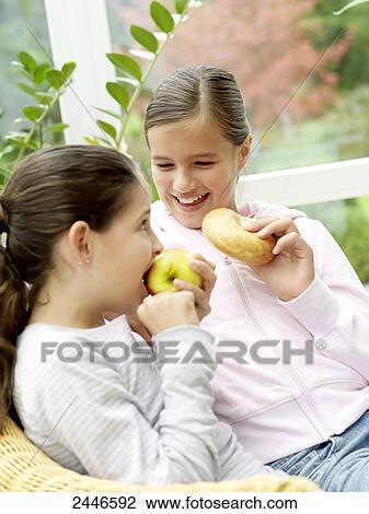 Close-up of two girls holding bagel and apple View Large Photo Image Stock Image - Close-up of two girls holding bagel and apple . Fotosearch