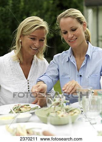 Stock Image - Close-up of woman serving food to her friend . Fotosearch