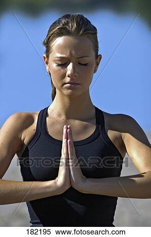 Stock Photography - Close-up of young woman doing yoga on lake beach . Fotosearch