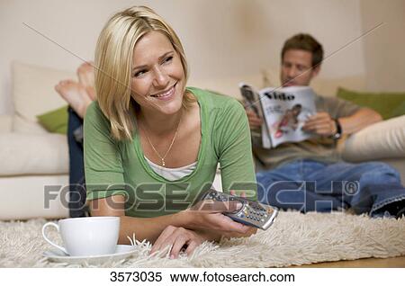 Couple at home with remote control and magazine View Large Photo Image Stock Photography - Couple at home with remote control and magazine . Fotosearch