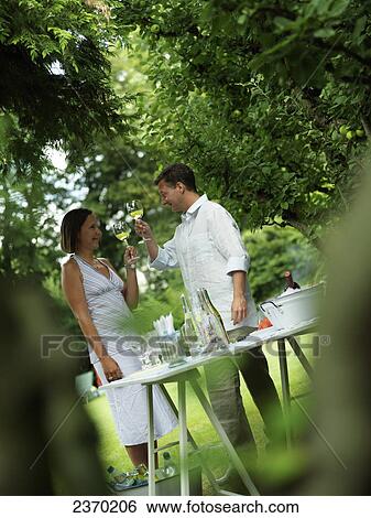 Couple toasting with wineglasses in garden View Large Photo Image Stock Photograph - Couple toasting with wineglasses in garden . Fotosearch