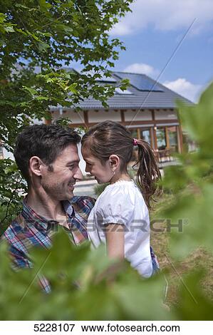 Stock Photo - Father with daughter in front of Lehner energy house, Poing, Bavaria, Germany, Europe . Fotosearch