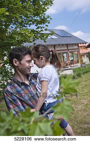 Stock Photograph - Father with daughter in front of Lehner energy house, Poing, Bavaria, Germany, Europe . Fotosearch
