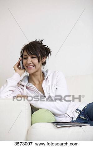Stock Photo - Happy woman in living room on the phone . Fotosearch
