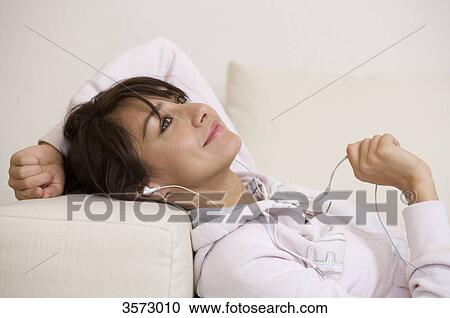 Stock Image - Happy woman in living room wearing headphones . Fotosearch