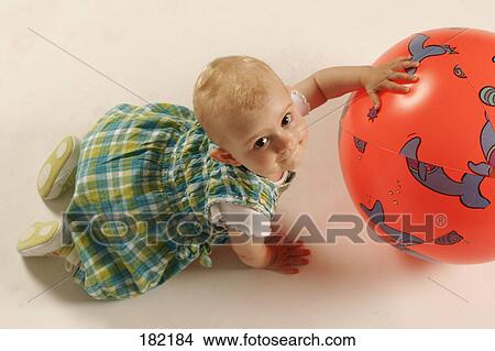 Picture - High angle view of baby girl playing with red ball . Fotosearch