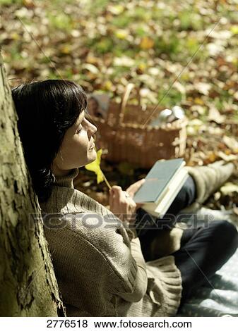 Stock Photo - High angle view of mature woman resting against tree . Fotosearch