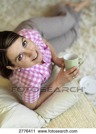 Stock Image - High angle view of woman reclining on floor and smiling . Fotosearch