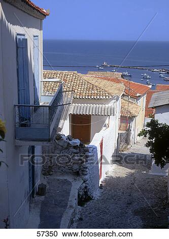 Stock Image - Houses along alley with Mediterranean sea in background, Peloponnese, Greece . Fotosearch