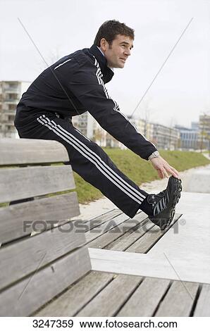 Stock Photo - Jogger making warm-up exercises, side view . Fotosearch