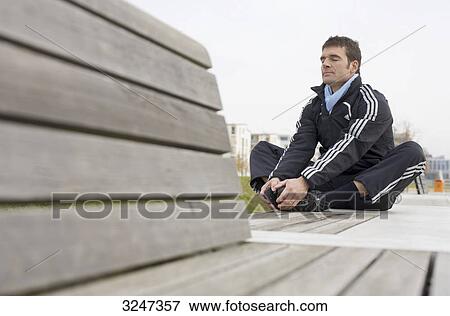 Jogger making warm-up exercises, low-angle view View Large Photo Image Stock Photo - Jogger making warm-up exercises, low-angle view . Fotosearch