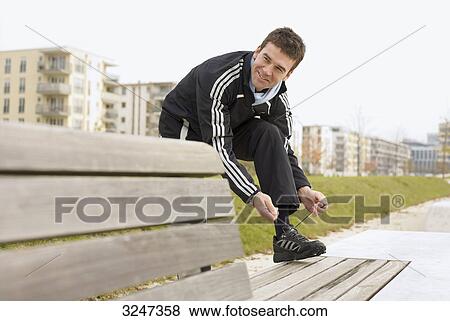 Stock Photo - Jogger tightening running shoe, horizontal format . Fotosearch