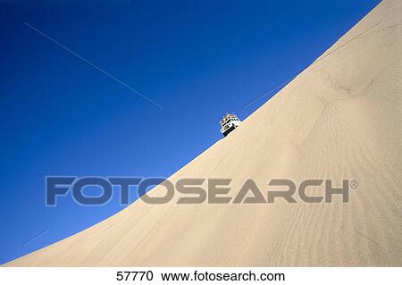 Stock Image - Low angle view of a SUV in the desert . Fotosearch