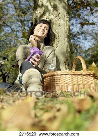 Low angle view of mature woman resting against tree and smiling View Large Photo Image Stock Image - Low angle view of mature woman resting against tree and smiling . Fotosearch