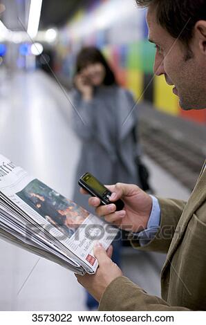 Man at subway station with newspaper and cell phone View Large Photo Image Stock Image - Man at subway station with newspaper and cell phone . Fotosearch
