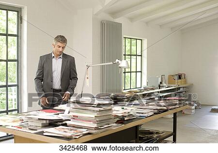 Man looking at magazines and books on a table View Large Photo Image Stock Photo - Man looking at magazines and books on a table . Fotosearch