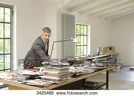 Stock Photograph - Man looking at magazines and books on a table . Fotosearch