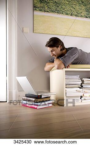 Man lying on a shelf and looking at a notebook, low angle view View Large Photo Image Stock Image - Man lying on a shelf and looking at a notebook, low angle view . Fotosearch