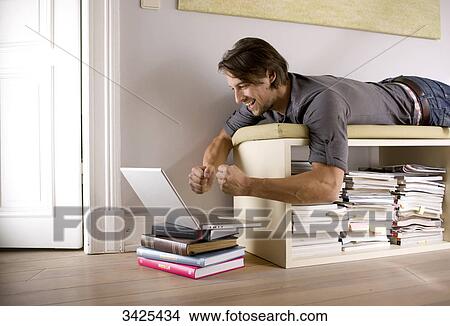 Man lying on a shelf and using a notebook, low angle view View Large Photo Image Picture - Man lying on a shelf and using a notebook, low angle view . Fotosearch