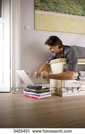 Stock Image - Man lying on a shelf and using a notebook, low angle view . Fotosearch
