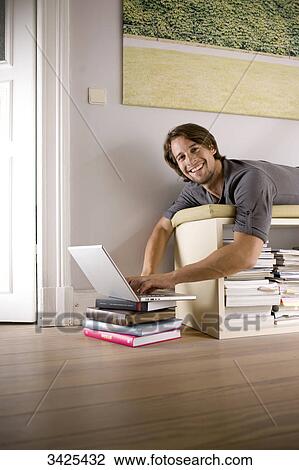 Man lying on a shelf and using a notebook, low angle view View Large Photo Image Stock Image - Man lying on a shelf and using a notebook, low angle view . Fotosearch