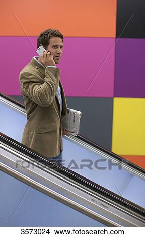 Picture - Man on the phone on escalator . Fotosearch