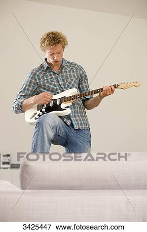 Man playing e-guitar in his apartment, low angle view View Large Photo Image Stock Photo - Man playing e-guitar in his apartment, low angle view . Fotosearch