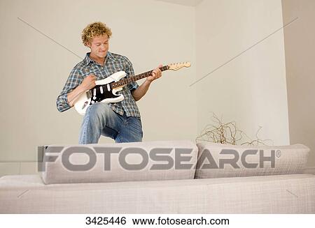 Man playing e-guitar in his apartment, low angle view View Large Photo Image Stock Photograph - Man playing e-guitar in his apartment, low angle view . Fotosearch